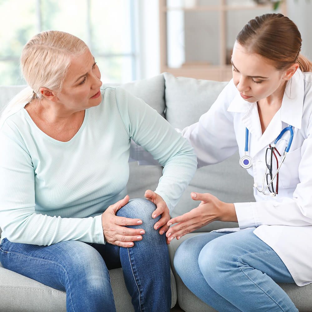 A woman holds onto her knee at a doctor's office