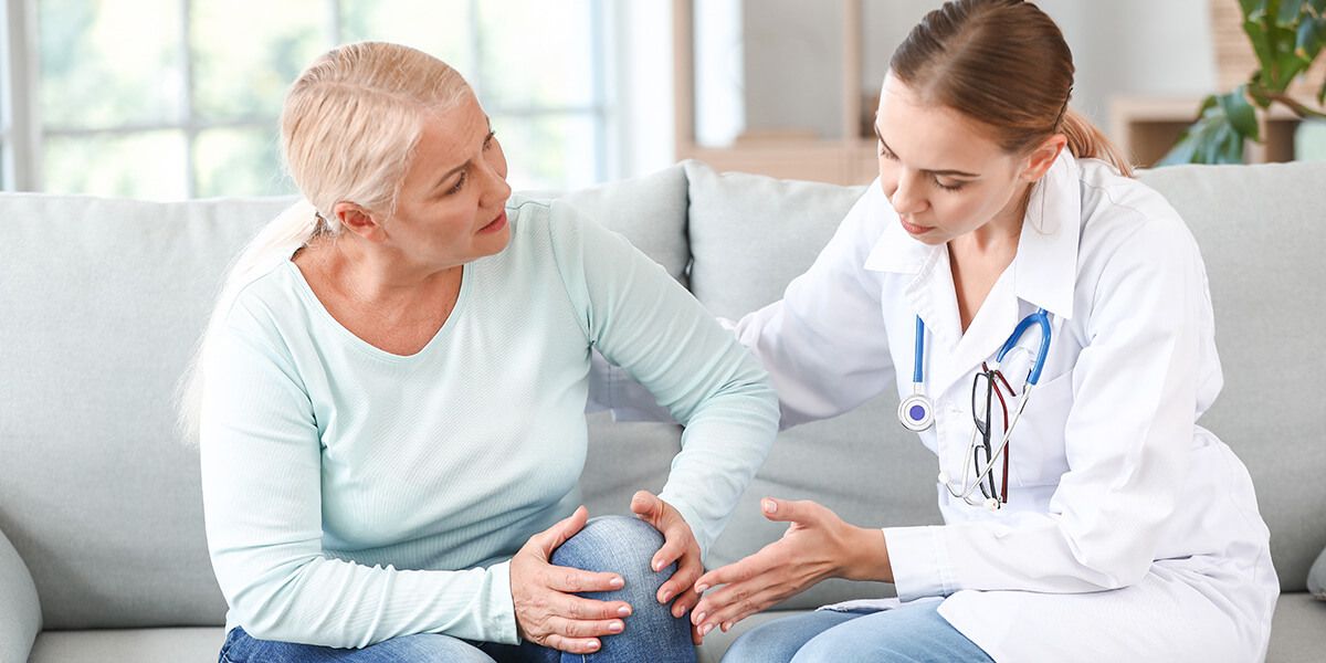 A patient holds her left knee with her hands and complains of pain in that knee at a doctor's appointment