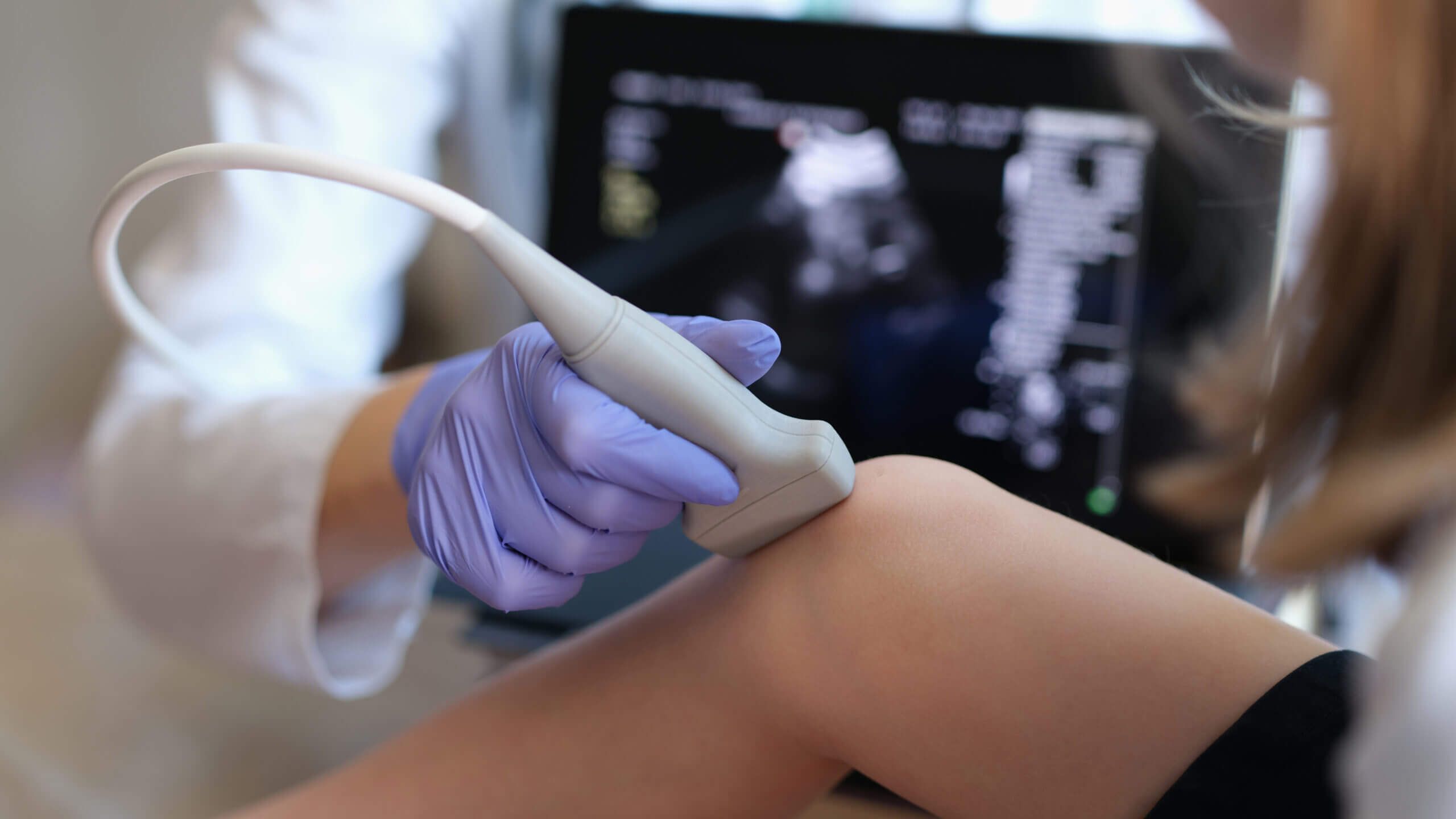 Doctor conducting ultrasound examination of knee joint in child closeup. Diagnosis of bone diseases in children concept